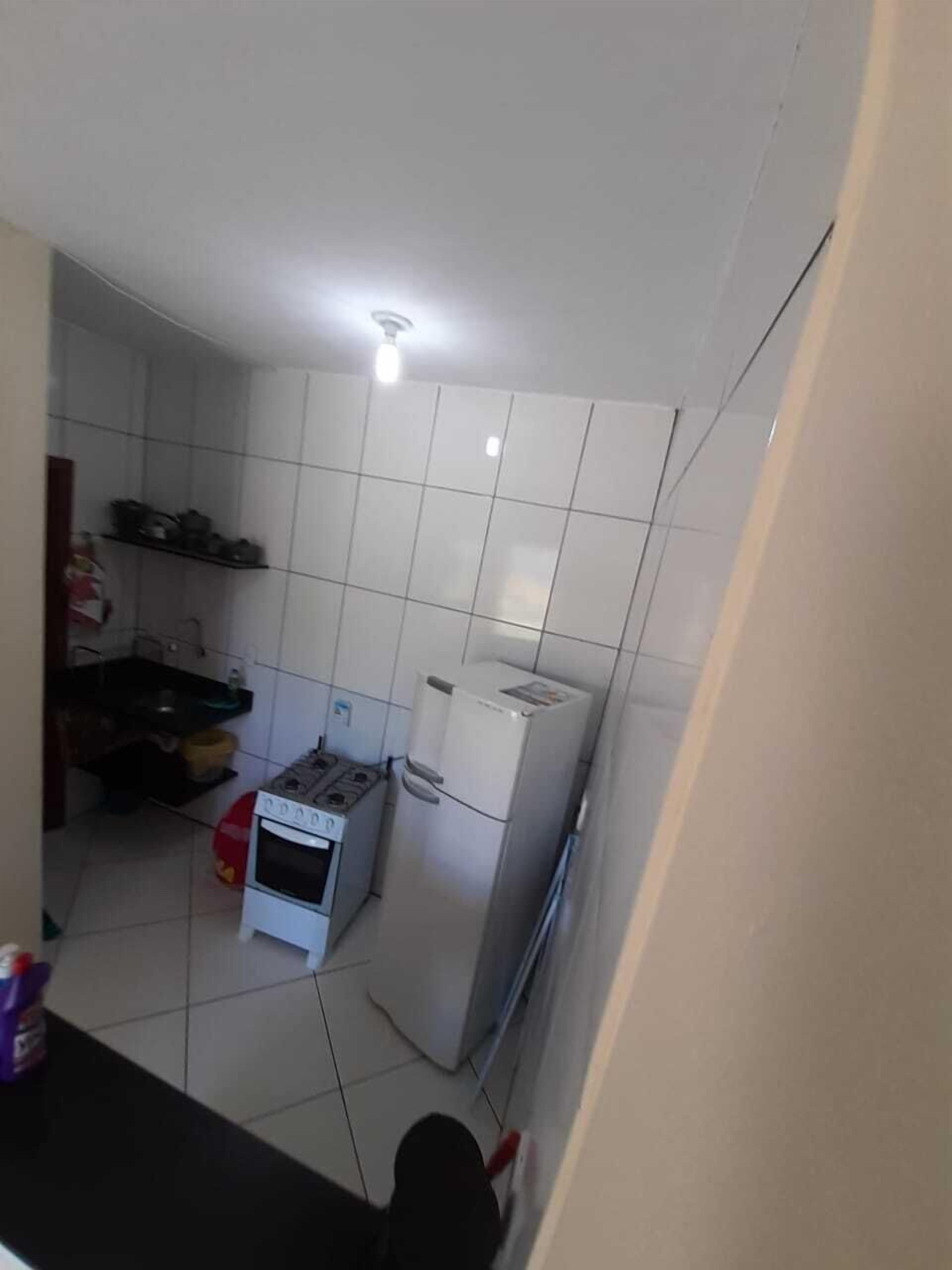 Una cocina compacta con azulejos blancos, cocina a gas, refrigerador y horno pequeño.