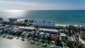 An aerial view of a coastal town with a marina, a large hotel with multiple floors, and a beach in the background. - Sunset Beach Condo (Treasure Island)
