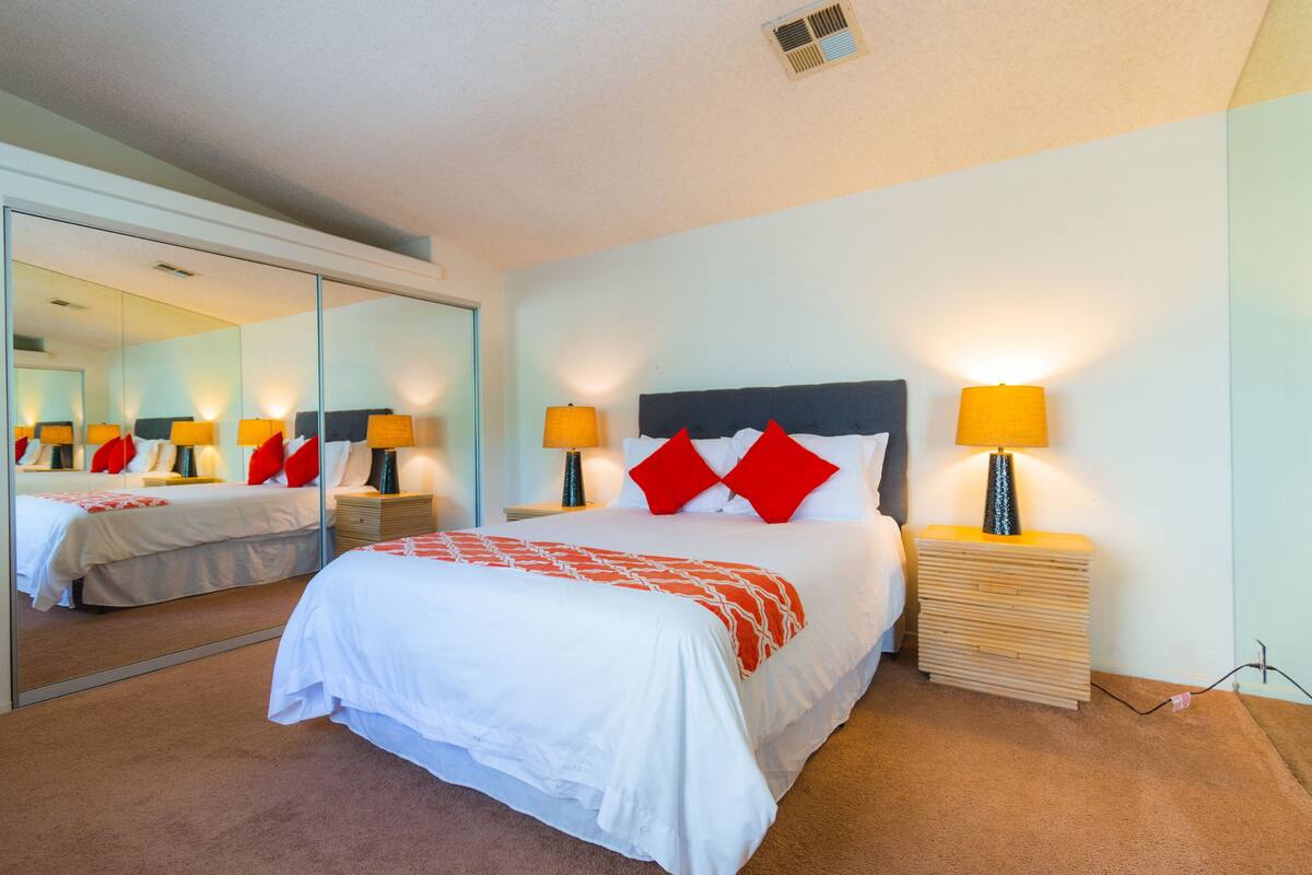 A hotel room with a large bed, two bedside tables, a mirror, and a nightstand.