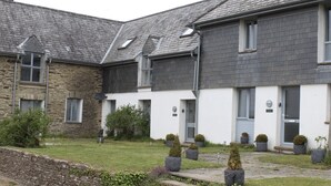 Uma fileira de casas de dois andares com fachadas de pedra e tijolo, um gramado e vasos de plantas.