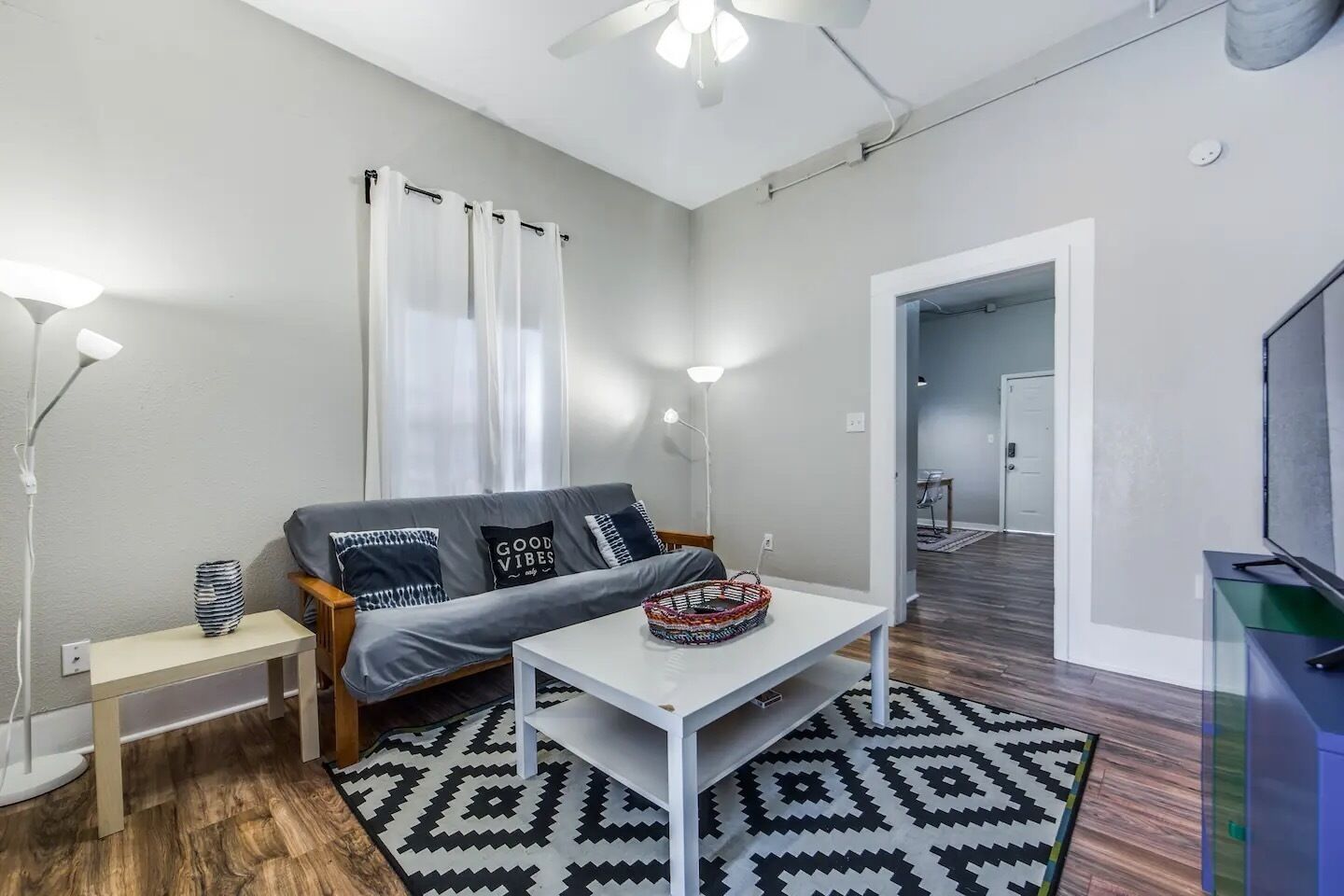 A modern living room with a grey sofa, a white coffee table, and a patterned rug.