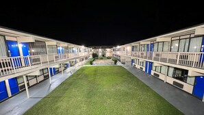 A motel with a central lawn, multiple balconies, and blue doors. - James River Inn & Suites (Newport News)