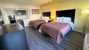 A hotel room with two beds, a desk, a TV, and a kitchenette. - James River Inn & Suites (Newport News)