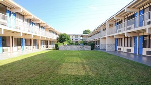 A motel with a central courtyard, multiple balconies, and a stone wall. - James River Inn & Suites (Newport News)