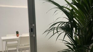Een kamer met een schuifdeur, een witte tafel met een plant in pot en een witte stoel.