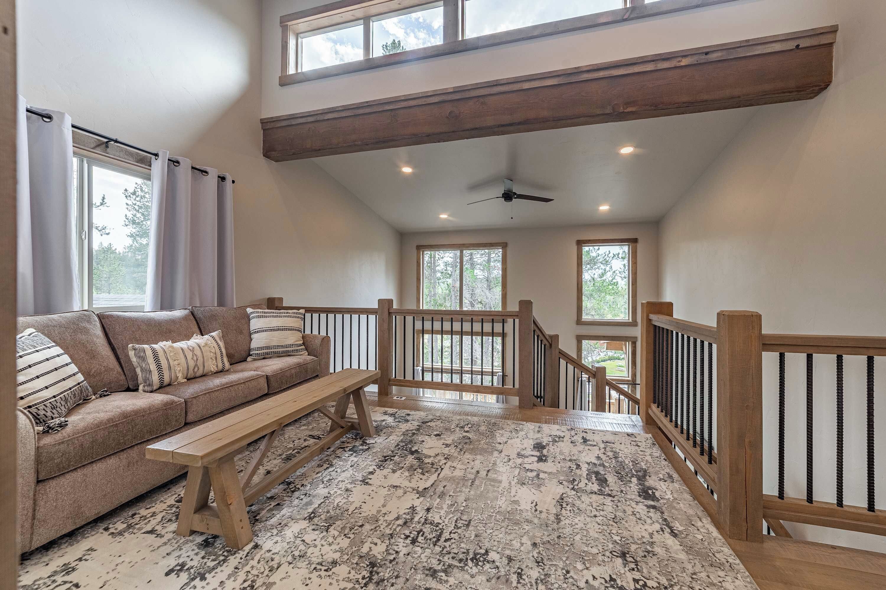 Ein geräumiger Loft mit hohen Decken, einer Holztreppe, einem Sofa und einer Bank.