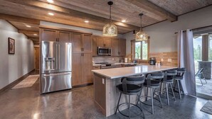 Una cucina moderna con mobili in legno, elettrodomestici in acciaio inossidabile e un'isola centrale con sgabelli da bar.