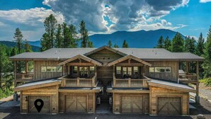 Un'ampia baita di legno con diversi garage, un portico coperto e vista sulle montagne.