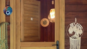 Una puerta de madera con un tirador metálico, un tapiz tejido y un adorno colgante sobre la puerta.