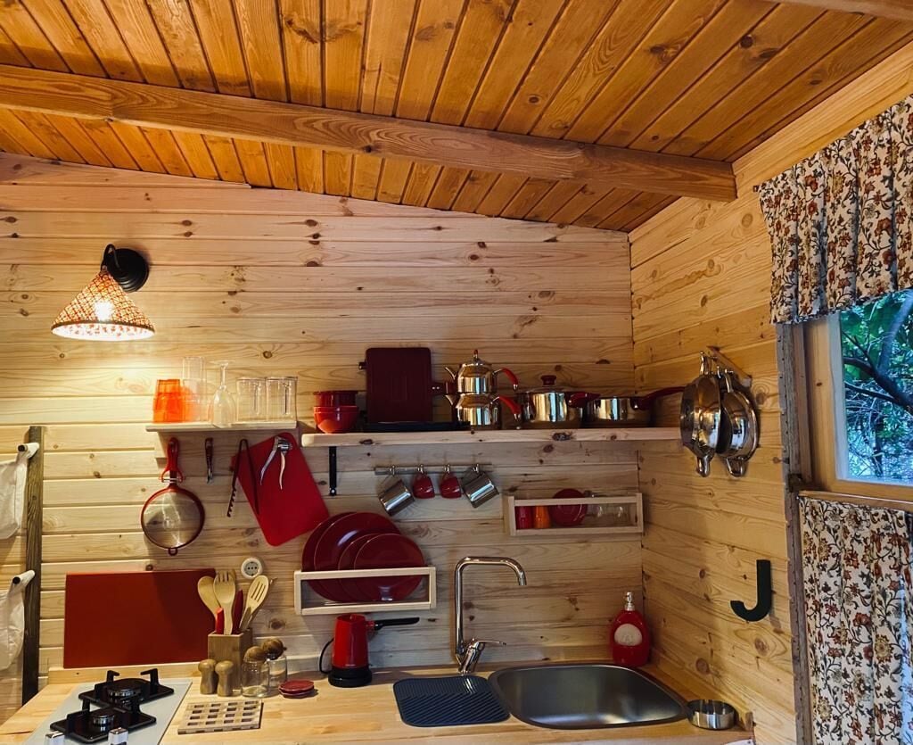 A wooden interior with a kitchen area including a sink, stove, and various utensils.