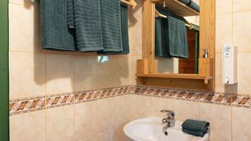 Un baño con un toallero de madera que sostiene dos toallas, un lavabo blanco y un espejo con marco de madera.