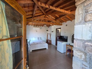Un dormitorio con cama, televisor, cómoda y pared de piedra.