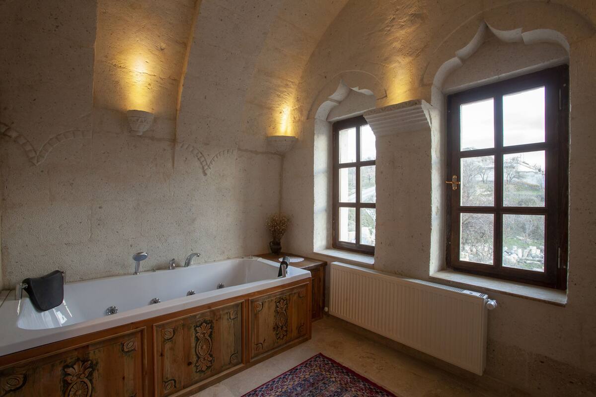 Casa de banho com uma banheira grande, janela e radiador.