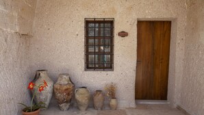 Un interior rústico con una puerta de madera, una ventana con rejas y varios objetos de cerámica en el suelo.