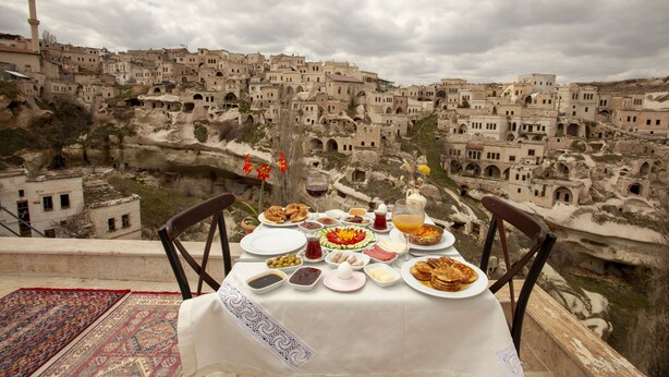Una mesa dispuesta con diversos platos y bebidas, con vistas a un pueblo histórico de arquitectura peculiar.