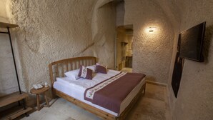 Un dormitorio con una cama de madera, una mesita de noche y un televisor instalado en la pared.