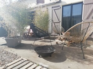 A patio area with outdoor furniture, including two chairs and a small table, surrounded by potted plants.