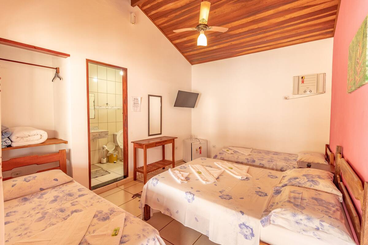 Une chambre avec deux lits, un plafond en bois, un ventilateur de plafond, une télévision et une petite table.