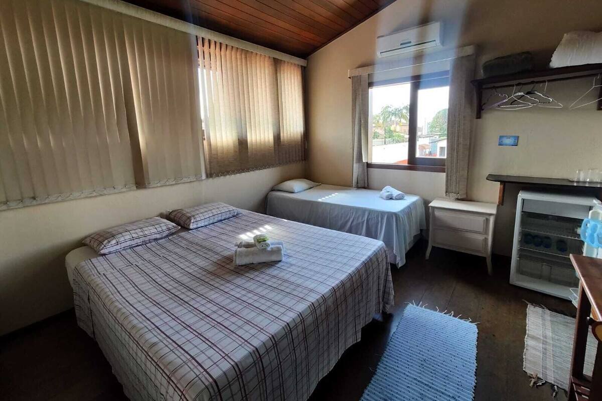 Une chambre avec deux lits, une kitchenette et une fenêtre avec des stores.