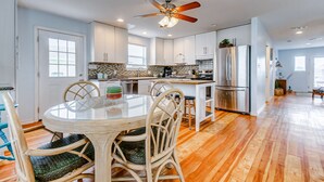 A modern kitchen with white cabinets, a central island, and a ceiling fan.