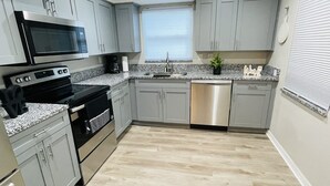 Eine moderne Küche mit grauen Schränken, Edelstahlgeräten, einer Granitarbeitsplatte und einem Holzboden.