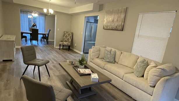 Ein modernes Wohnzimmer mit einer Couch, zwei Sesseln, einem Couchtisch und einem Essbereich im Hintergrund.