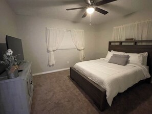 Cozy retreat with a single bed, dresser, and mirror, set against a window with white curtains.