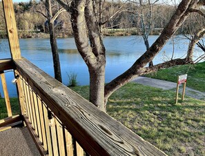 A wooden deck overlooking a lake with trees and a grassy area. - Spring River Waterfront Cabin - Walking Distance to Downtown Hardy & Loberg Park (Hardy)