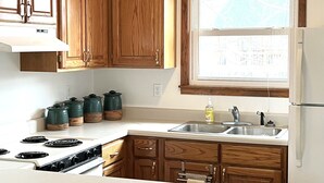 Una cocina con armarios de madera, encimera blanca, un lavabo y una ventana con vistas.