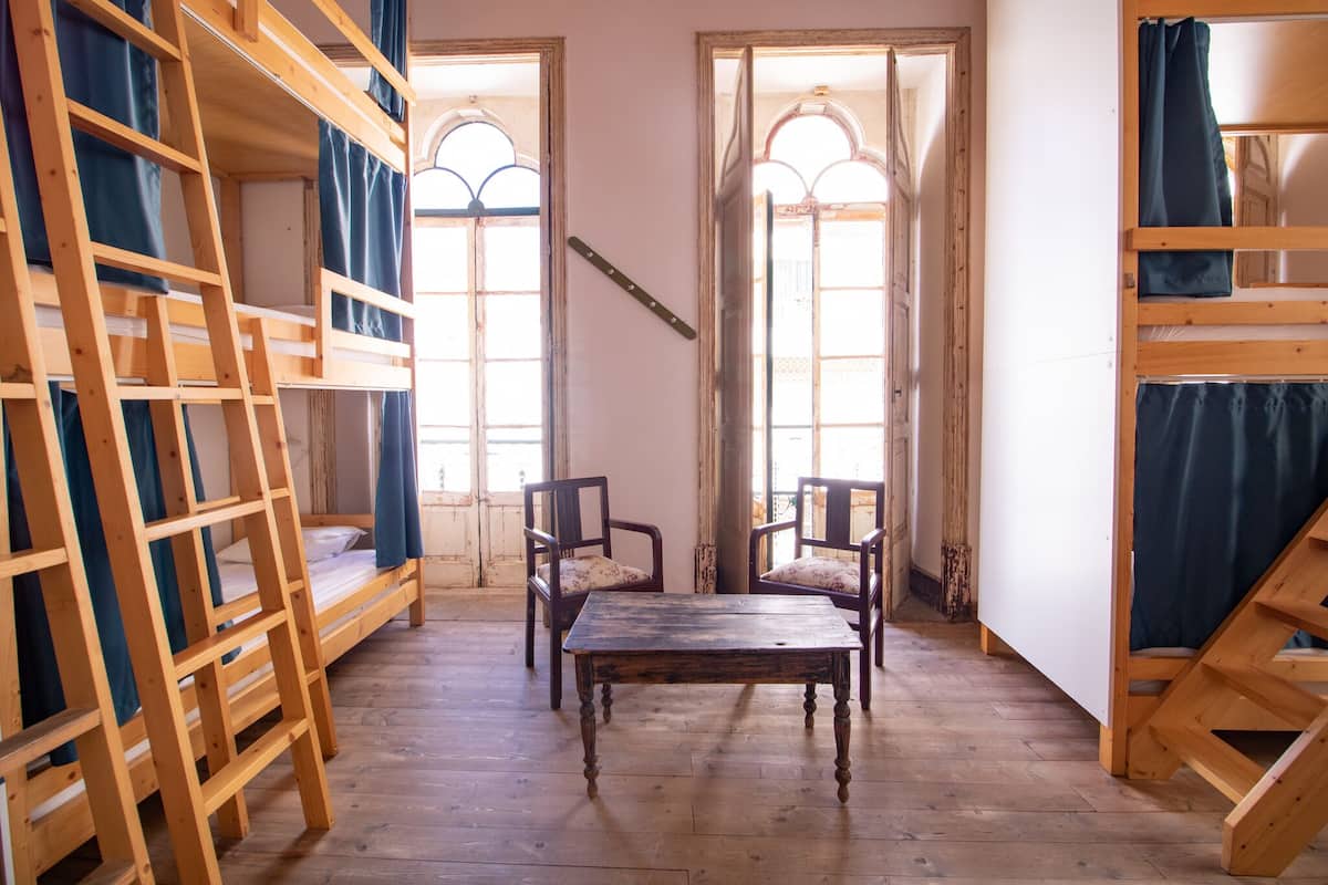 A room with bunk beds, a wooden table, and two chairs.