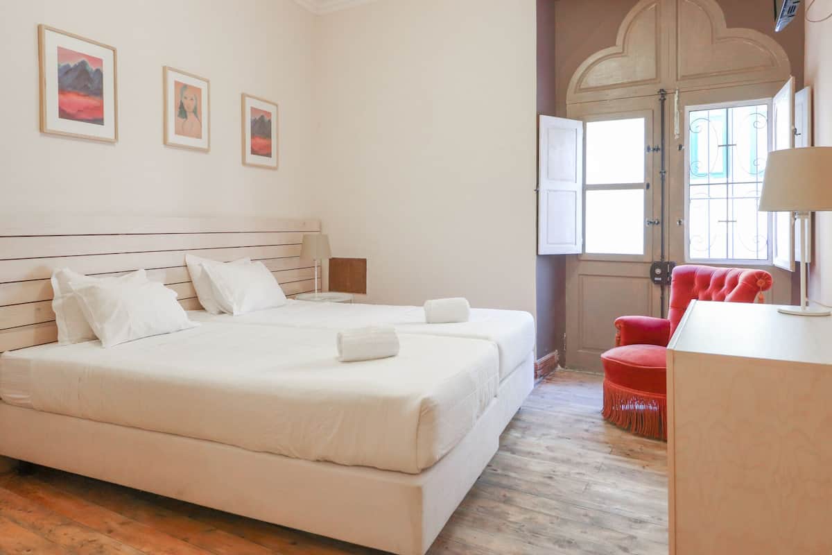 A bedroom with a large bed, a red chair, and a door with a decorative arch.