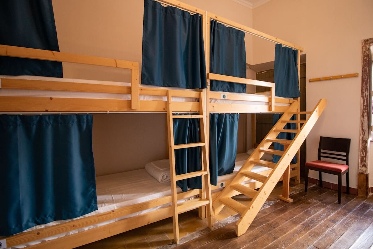 A bunk bed room with a wooden ladder and curtains.