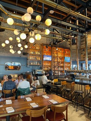 A restaurant with a bar area, wooden tables, and hanging spherical lights. - Beautiful  unit in the heart of Belmont Shores!!! (Long Beach)