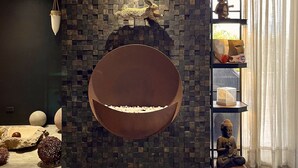 Ein modernes Interieur mit einer runden Sitzecke, einer Mosaikwand und einer Buddha-Statue.