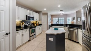 A modern kitchen with white cabinets, stainless steel appliances, and a central island.