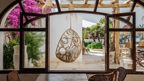 A room with a large arched window overlooking a garden with potted plants and a hanging decorative piece. - La Bohemia del Rio Hostal Boutique - Adults Only (Santa Eulalia del Rio)