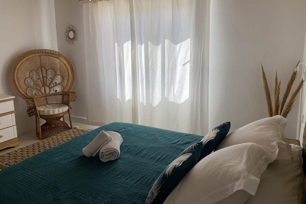 A bedroom with a bed, a chair, and a window with curtains.