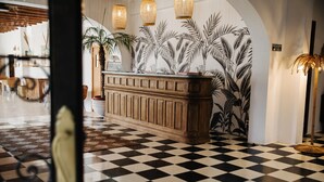 A lobby with a checkered floor, a wooden reception desk, and tropical wallpaper. - La Bohemia del Rio Hostal Boutique - Adults Only (Santa Eulalia del Rio)