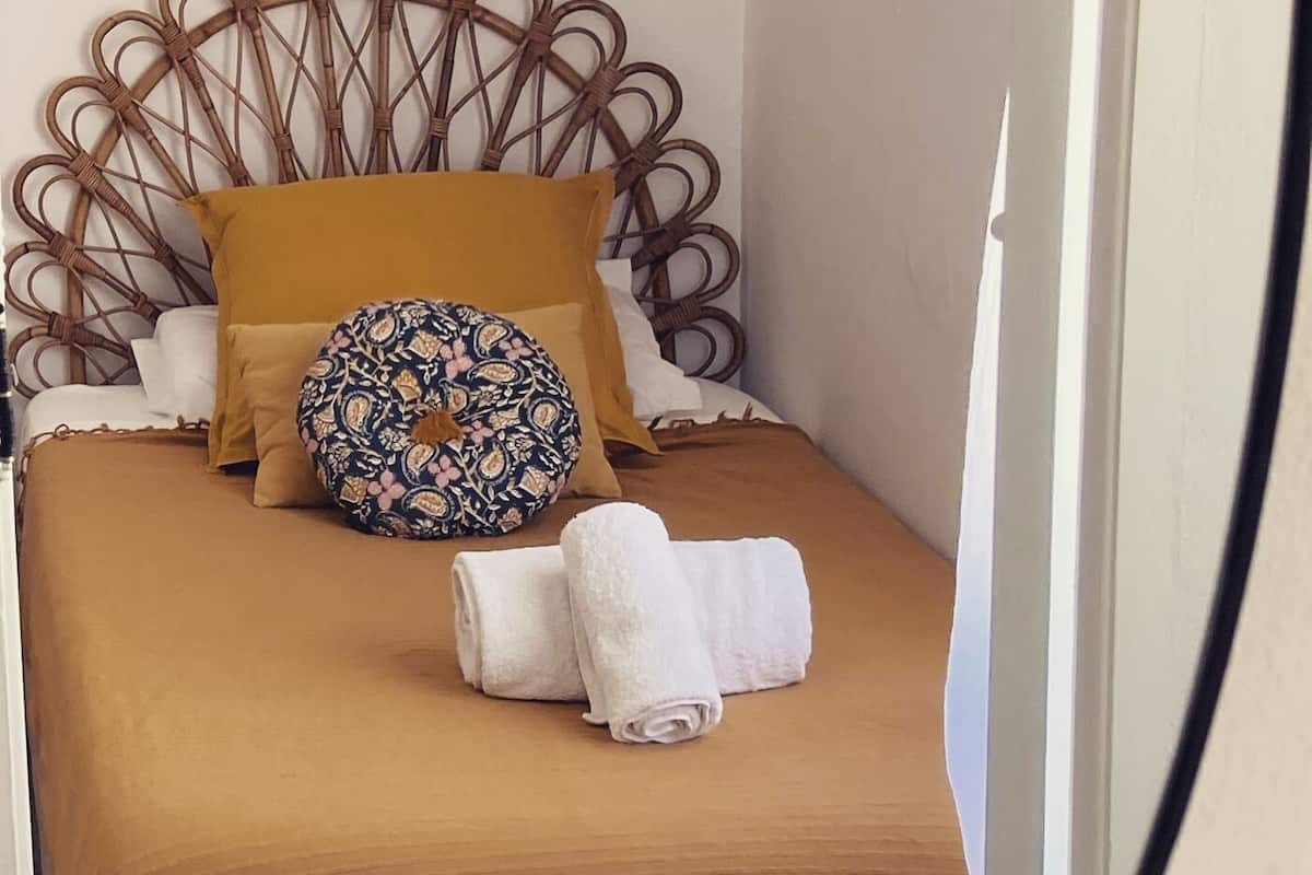 A neatly made bed with a brown bedspread, a patterned pillow, and a headboard with a circular design.