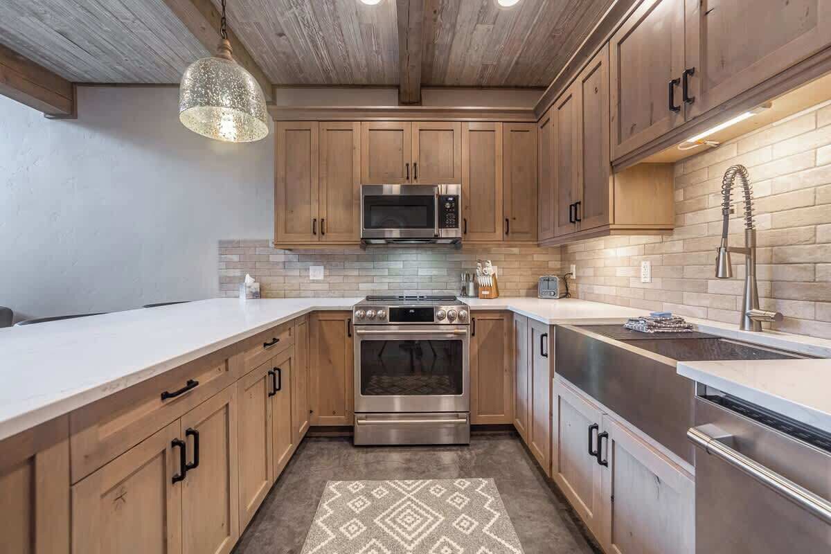 Una cucina moderna con mobili in legno, elettrodomestici in acciaio inossidabile e un tappeto decorato.