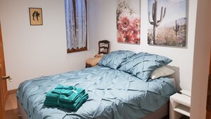 A bedroom with a bed, a nightstand, a window with curtains, and wall art. - Whole house (Belvedere)