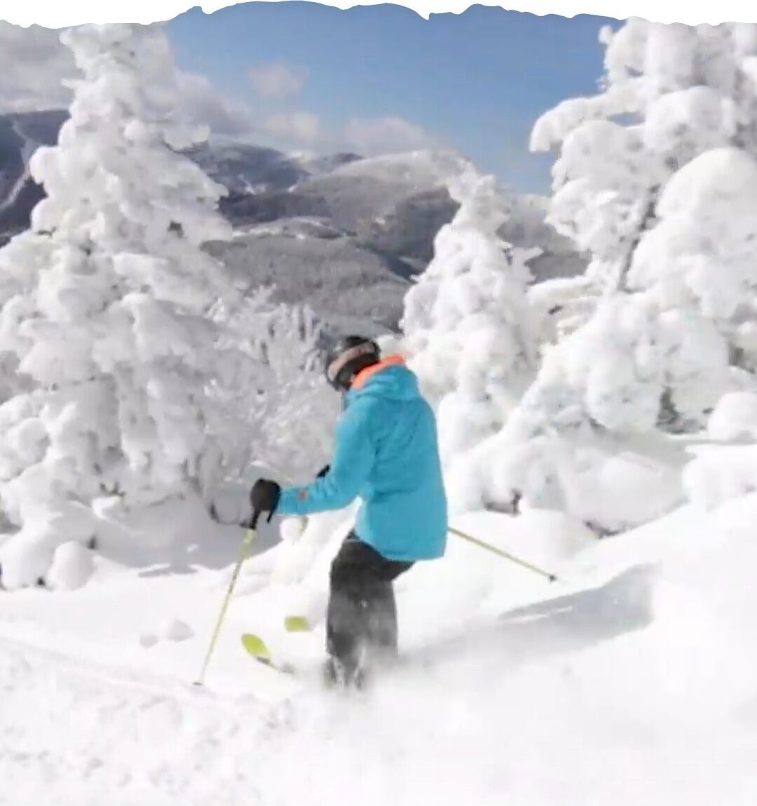 A person skiing in a snowy landscape with mountains in the background.