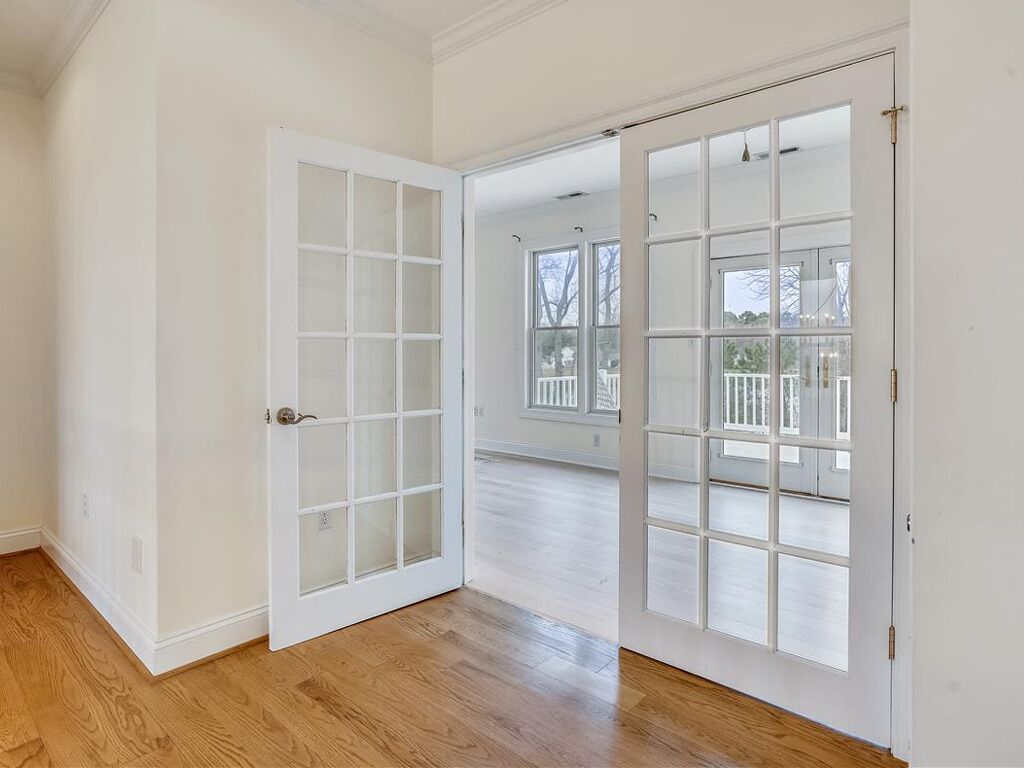 A room with a wooden floor, white walls, and a large sliding glass door leading to an outdoor deck.