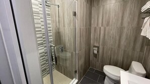 Een moderne badkamer met een douchecabine van glas, een toilet en een wastafel.