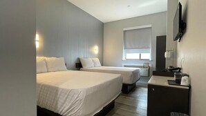 Een hotelkamer met twee bedden, een bureau, een televisie en een raam.