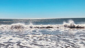 Une plage où les vagues se brisent sur le rivage sous un ciel dégagé.