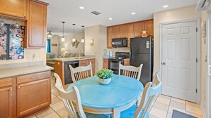 A modern kitchen with wooden cabinets, a dining table with chairs, a refrigerator, and a microwave. - 3 Min Walk to Beach-Perfect for Families-Pet Friendly (North Myrtle Beach)