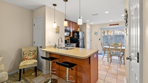 A kitchen with a bar area, a dining table with chairs, and a view of the backyard. - 3 Min Walk to Beach-Perfect for Families-Pet Friendly (North Myrtle Beach)