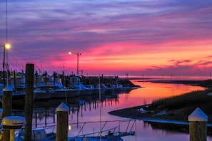 Un puerto deportivo al atardecer con barcos amarrados, un muelle y agua tranquila que refleja el cielo.