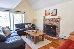 Una sala de estar con chimenea, un sofá, una mesita de centro y un tablero de ajedrez.